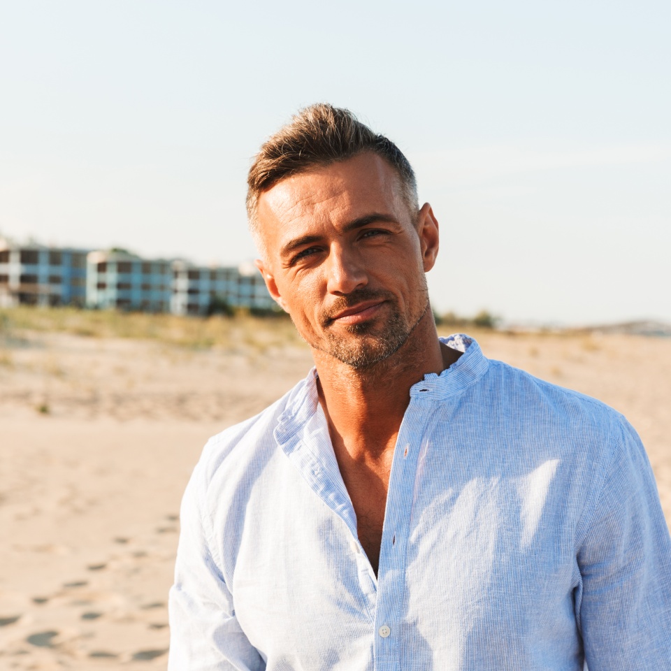 Portrait of a handsome man in shirt standing at the beach