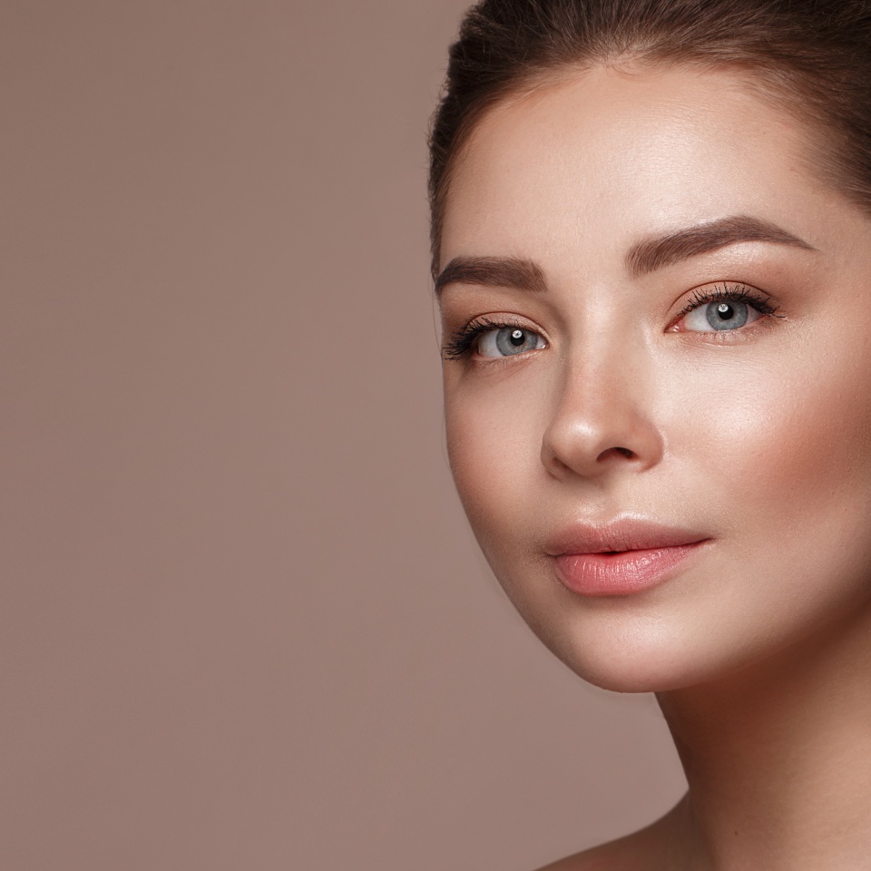 Beautiful young girl with natural nude make-up with cosmetic in hands. Beauty face. Photo taken in studio