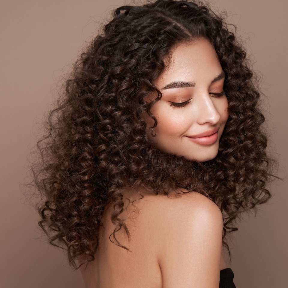 Fashion studio portrait of beautiful smiling woman with afro curly hairstyle. Fashion and beauty