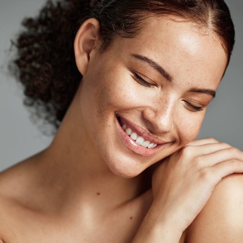 Face, beauty and skin with a model black woman in studio on a gray background to promote natural care. Facial, wellness and makeup with an attractive young female happy with her skincare product