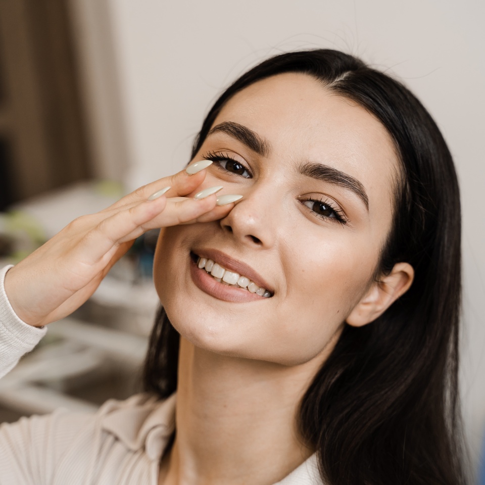 Girl touches her nose and smiles after septoplasty nose surgery correction deformities of the nasal septum. Happy patient of ENT doctor