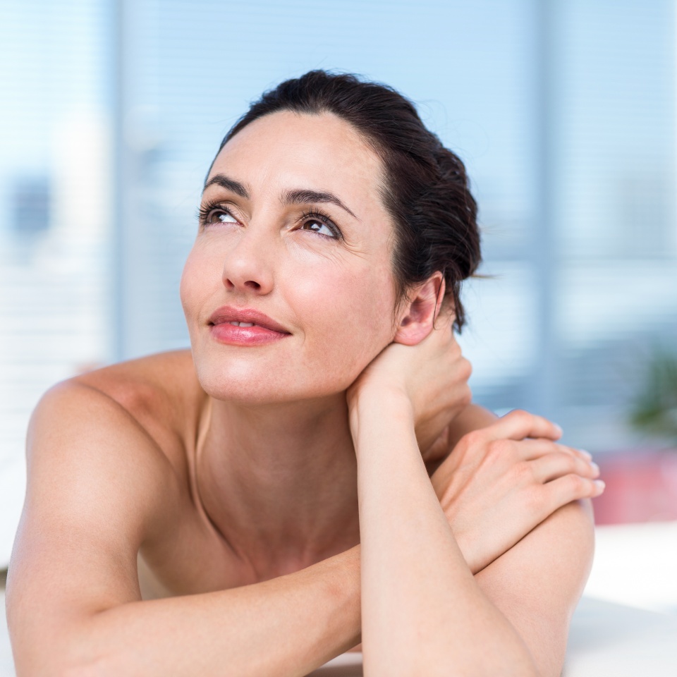 Smiling brunette relaxing on massage table in a healthy spa